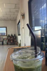 มัทฉะลาเต้เย็นในแก้วพลาสติกใส ฝาปิดใส หลอดสีดำ ตัวเครื่องดื่มมีสีเขียวอ่อนของมัทฉะผสมกับน้ำแข็ง ดูเข้มข้นและเย็นสดชื่น แก้วนี้วางอยู่บนโต๊ะทำงานไม้ ด้านหลังโต๊ะจะเห็นจอมอนิเตอร์คอมพิวเตอร์และลำโพงสีน้ำเงินขนาดกลางที่มีปุ่มกลมขนาดใหญ่  ตัวห้องมีพื้นที่กว้าง ดูสะอาด เป็นห้องที่มีแสงธรรมชาติส่องเข้ามาจากหน้าต่างกระจกบานใหญ่ทั้งสองฝั่ง ผนังและเพดานห้องเป็นสีขาว มีต้นไม้เล็ก ๆ และของตกแต่ง ตรงมุมไกลของห้องมีโต๊ะหมู่บูชา จัดวางพระพุทธรูปและภาพถ่ายต่าง ๆ เป็นระเบียบ เหมาะแก่การพักผ่อนหรือทำงาน