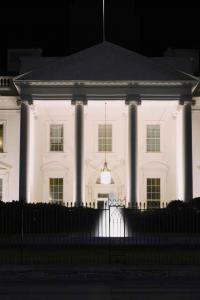 ทำเนียบขาวยามค่ำคืน แสงไฟขาวส่องตัวอาคารจนโดดเด่นท่ามกลางความมืด รั้วสีดำและเงาต้นไม้เปรียบเสมือนม่านแห่งความลับ ปกปิดเรื่องราวมากมายที่ซ่อนอยู่ภายใน