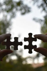 ภาพมือที่กำลังถือชิ้นส่วนจิ๊กซอว์ 2 ชิ้นที่แตกต่างกันแต่กำลังจะนำมาต่อกัน สื่อถึงคนที่มีนิสัยต่างกันแต่สามารถ "ลงล็อก" และเติมเต็มส่วนที่ขาดของกันและกันได้พอดี